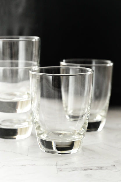 Set of clear glass tumblers on a marble surface with a dark background
