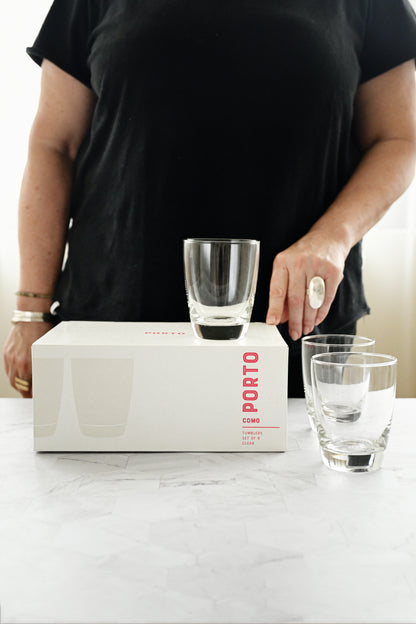 Person holding a glass above a Porto Cima wine box on a marble surface
