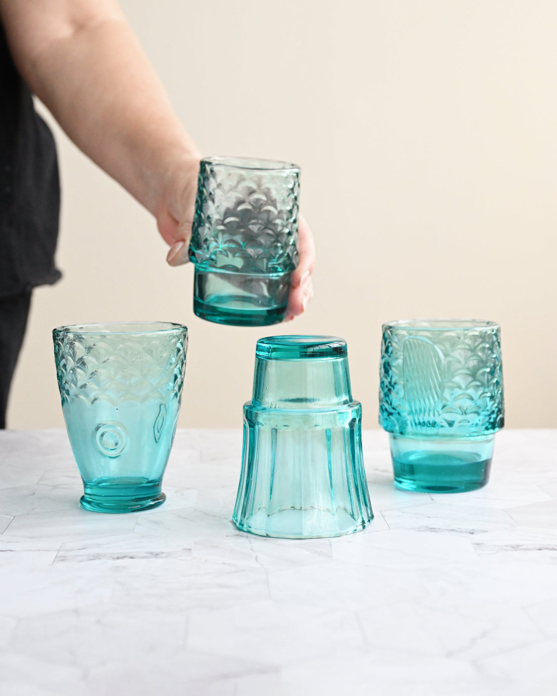 Set of five turquoise glass tumblers on a white surface with a blurred background