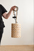 Person holding a woven lampshade against a plain background