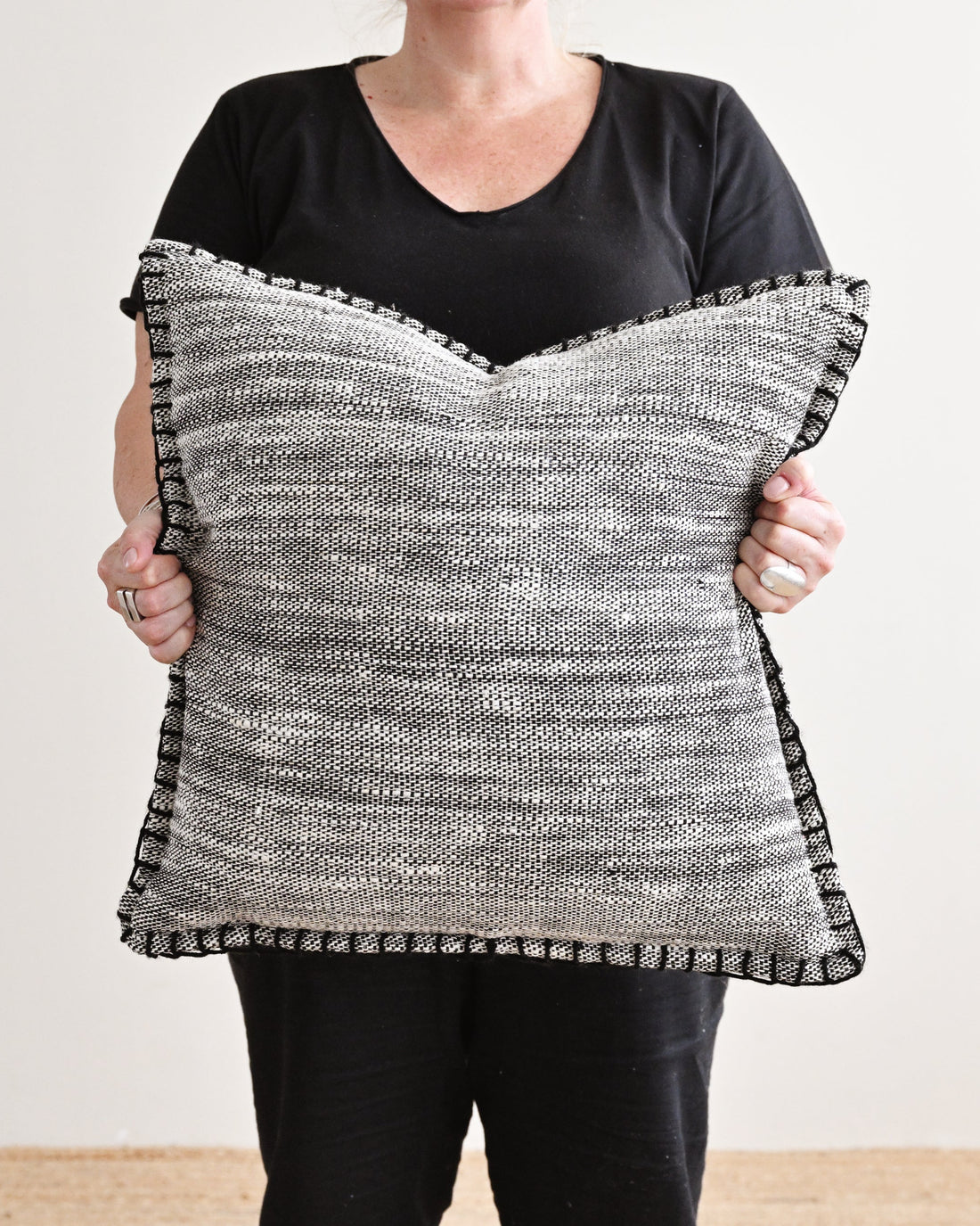 Person holding a black and white patterned pillow against a plain background