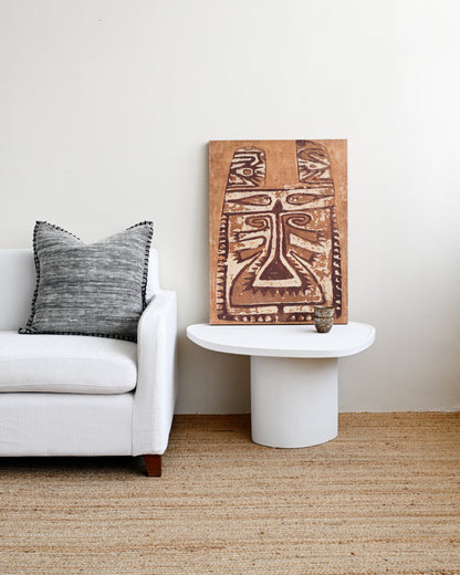 Living room with a white sofa, decorative pillow, and a wooden wall art piece.