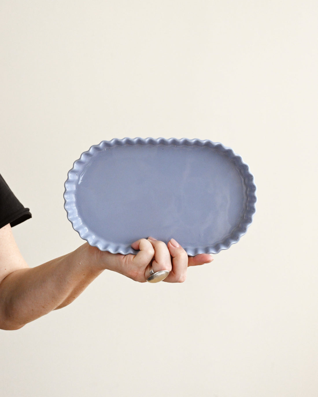 Person holding a blue ceramic plate against a beige background
