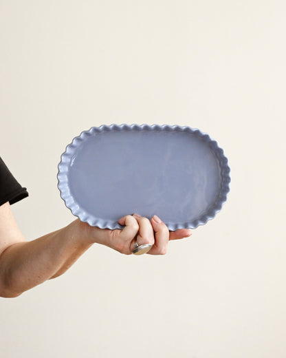 Person holding a blue ceramic plate against a beige background