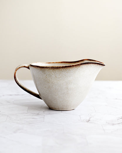 White ceramic pitcher with brown accents on a marble surface