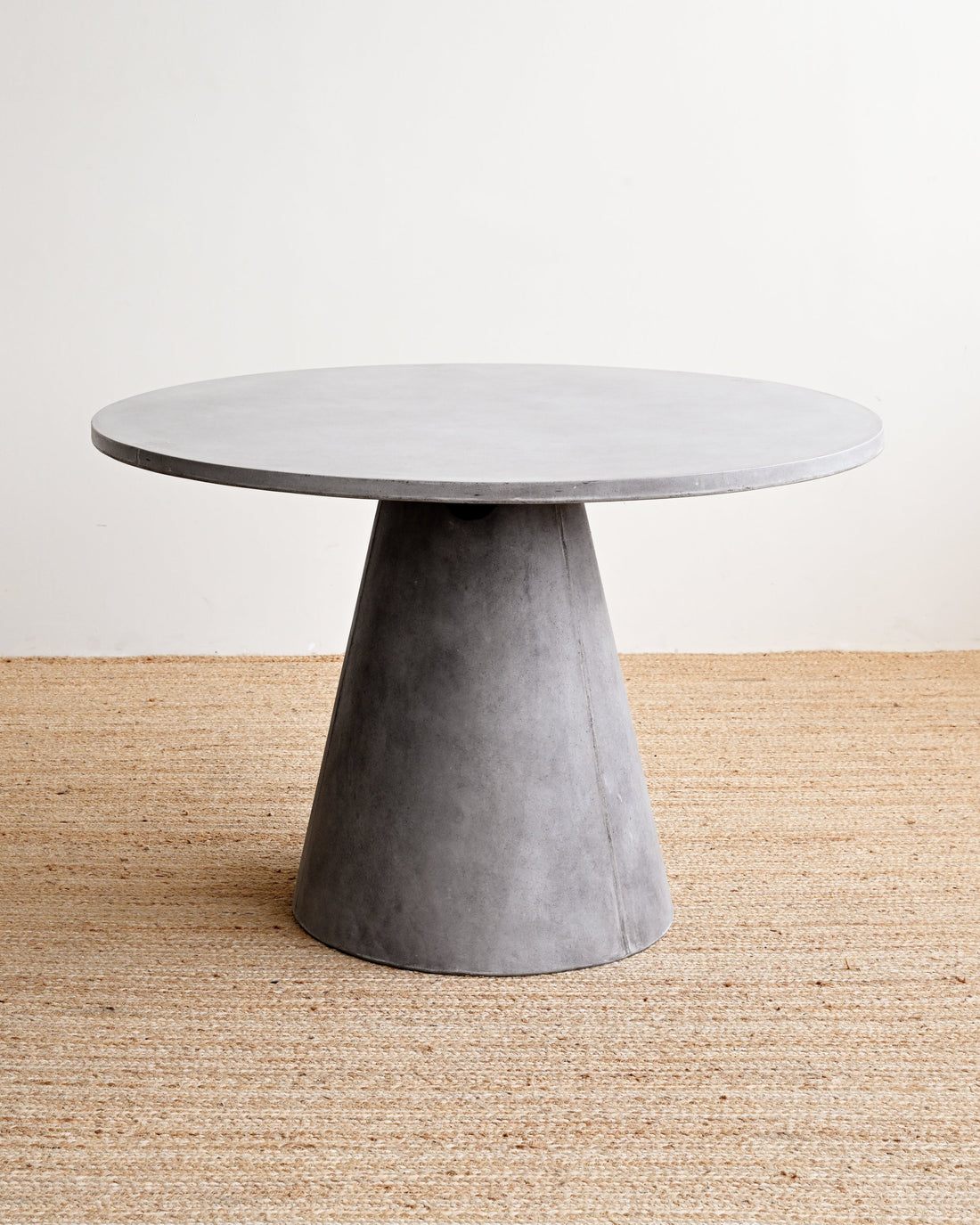 Round concrete table with a cylindrical base on a neutral background