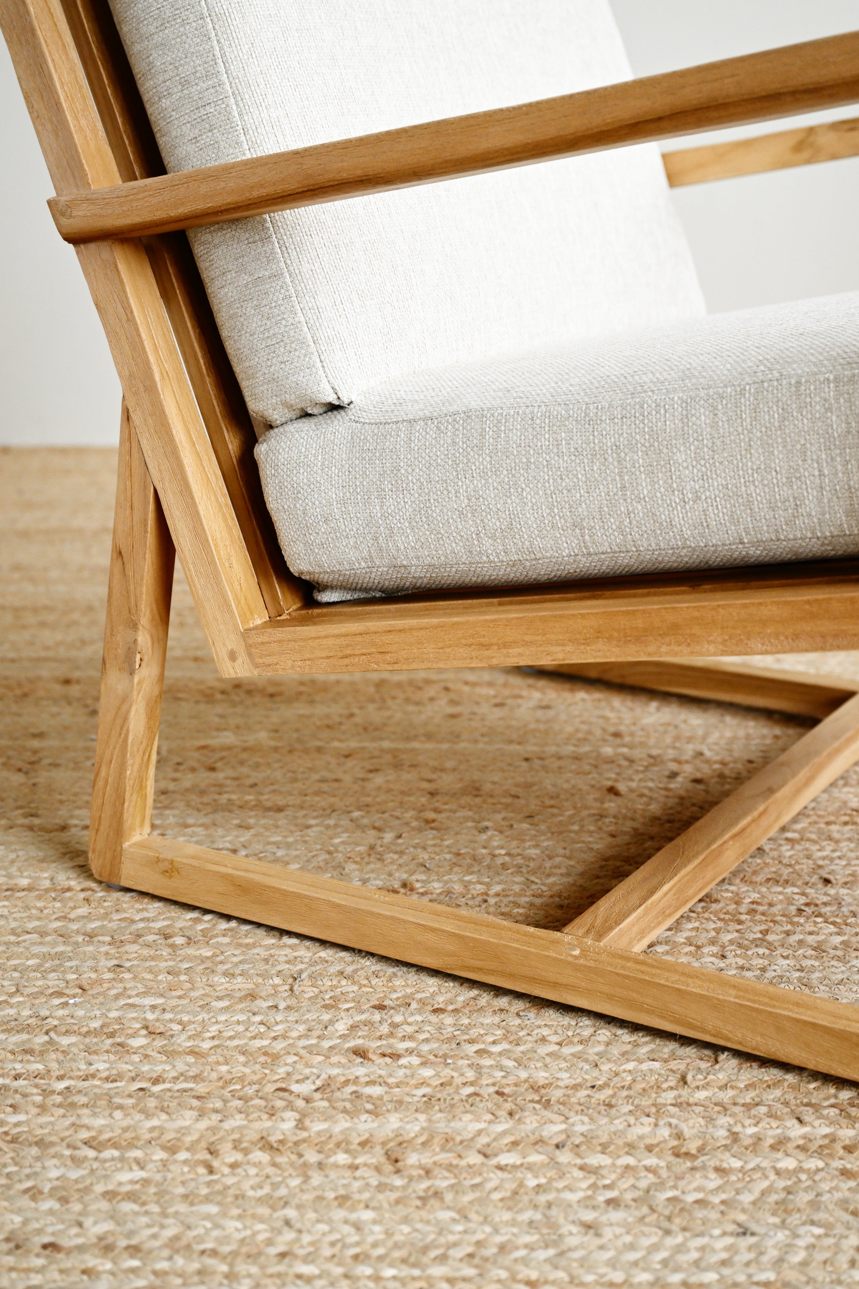 Wooden chair with white cushion on a textured floor