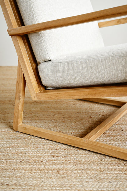 Wooden chair with white cushion on a textured floor