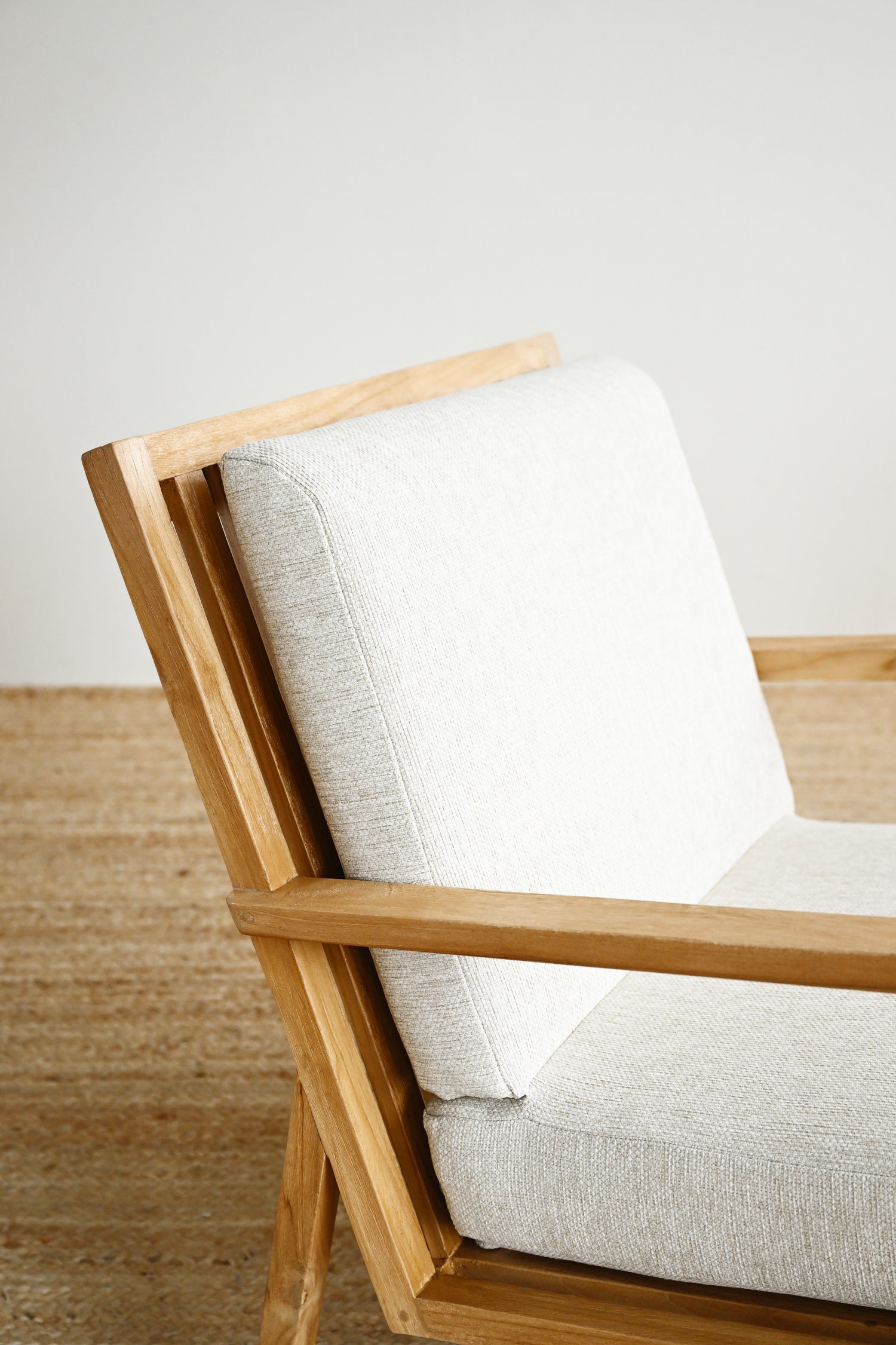 Wooden chair with white cushion on a wooden floor and light-colored wall background