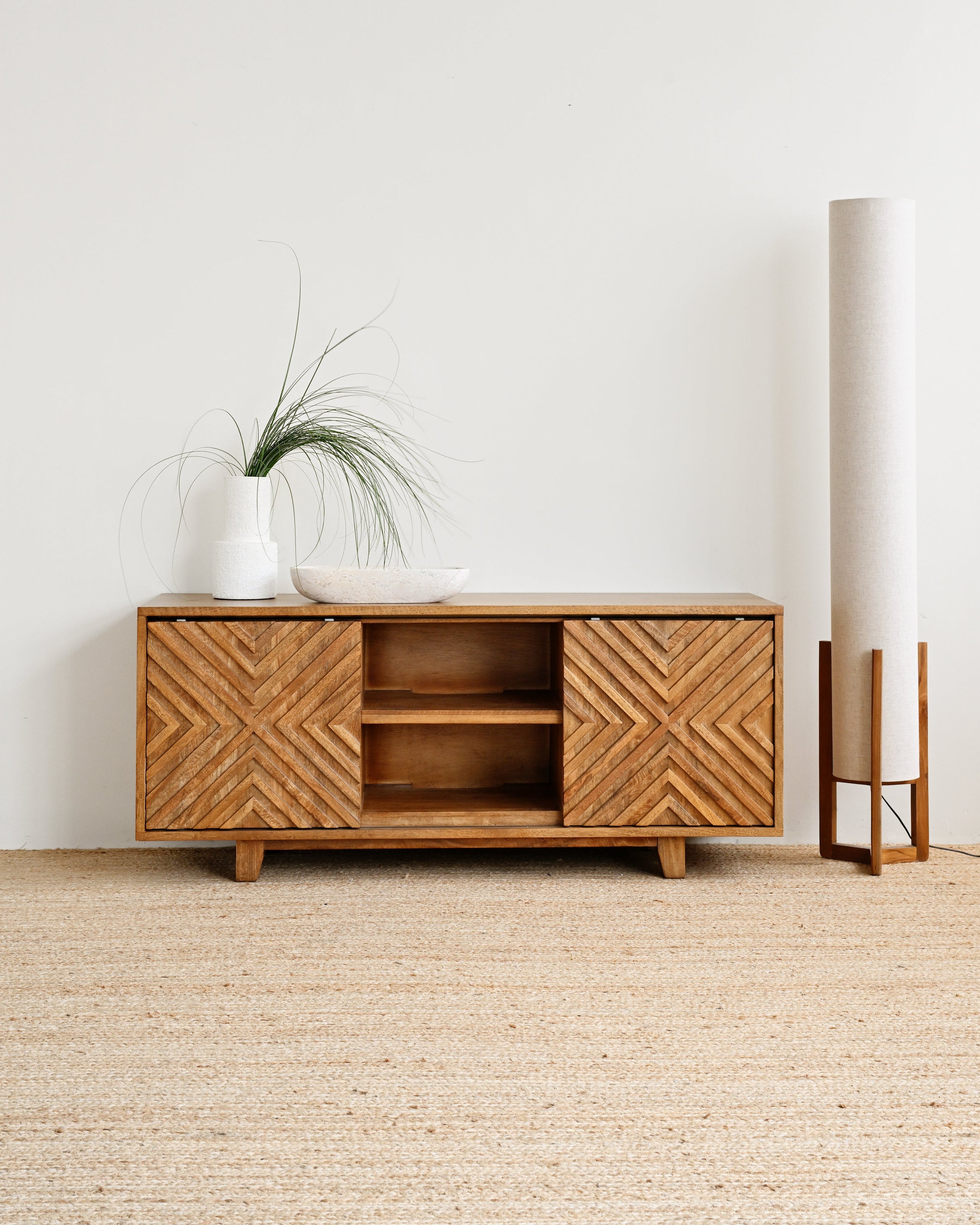 Wooden cabinet with decorative patterns in a minimalistic room.