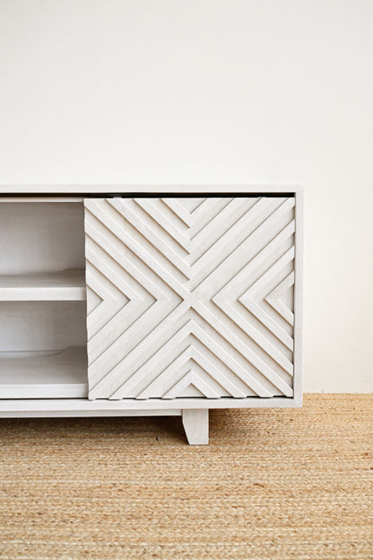 White cabinet with geometric pattern on a beige rug and white wall