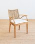 Woven chair with a white cushion on a textured floor