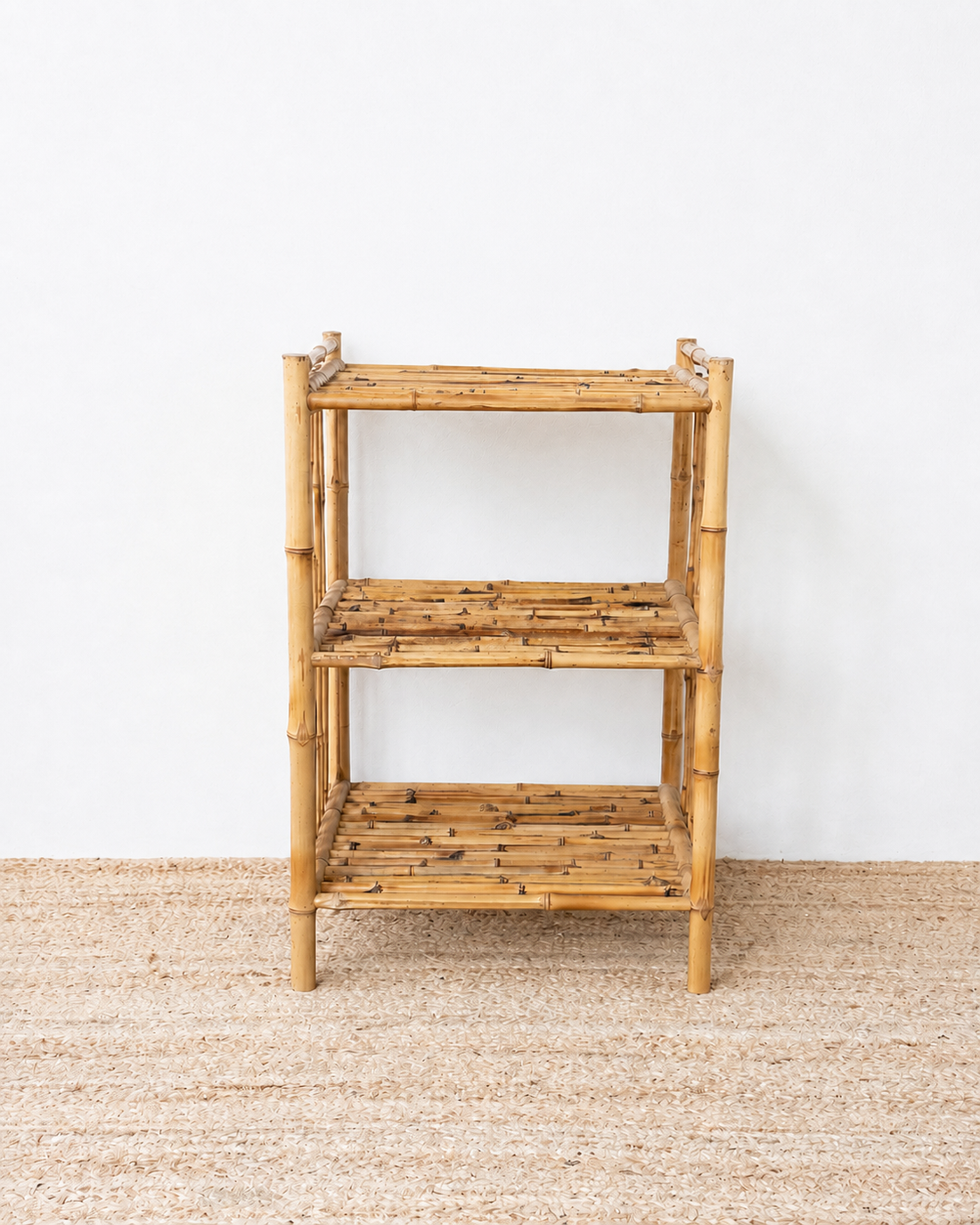 Bamboo shelf against a white wall on a textured floor