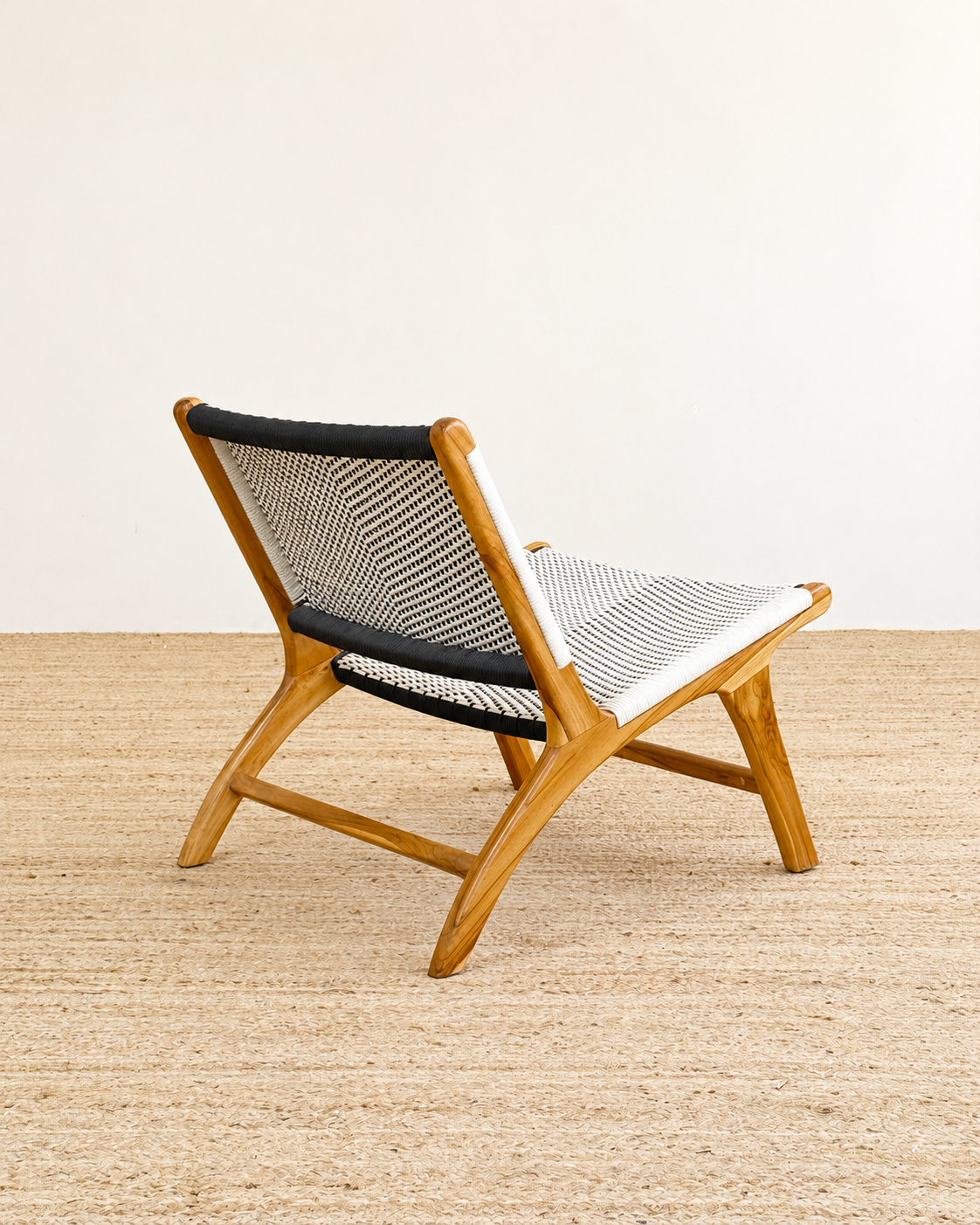 Wooden chair with black and white woven seat on a beige floor.