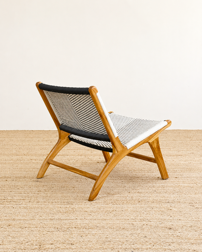 Wooden chair with black and white woven seat on a beige floor.