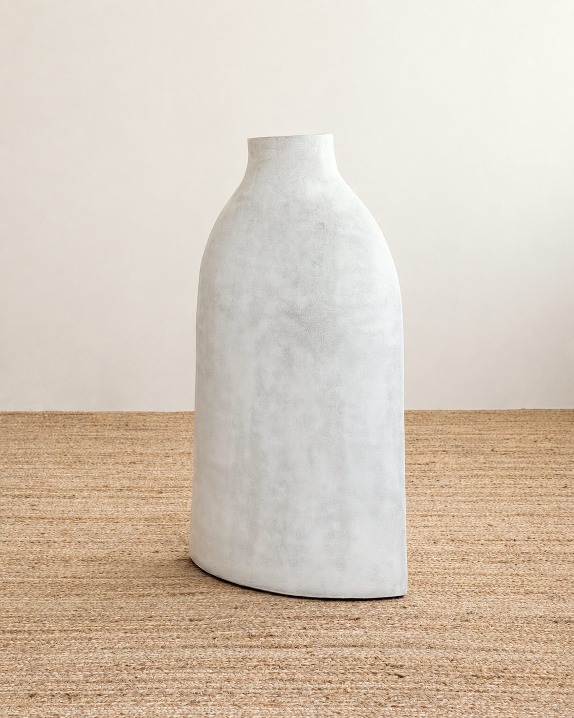 White textured vase on a woven surface with a neutral background