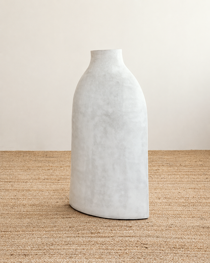 White textured vase on a woven surface with a neutral background