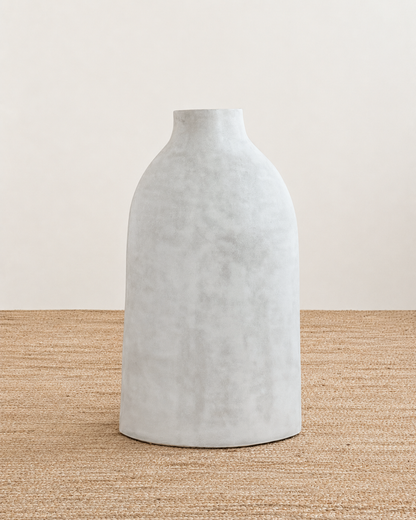 Gray textured vase on a beige surface with a neutral background