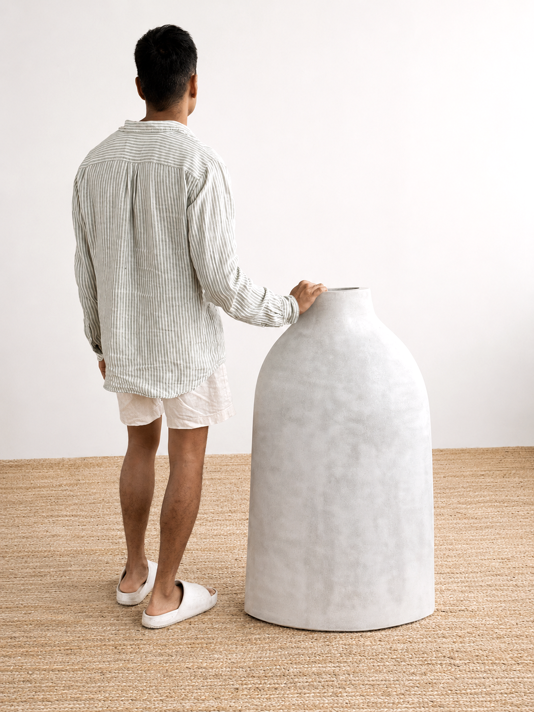 Person interacting with a large white textured stool in a minimalistic setting