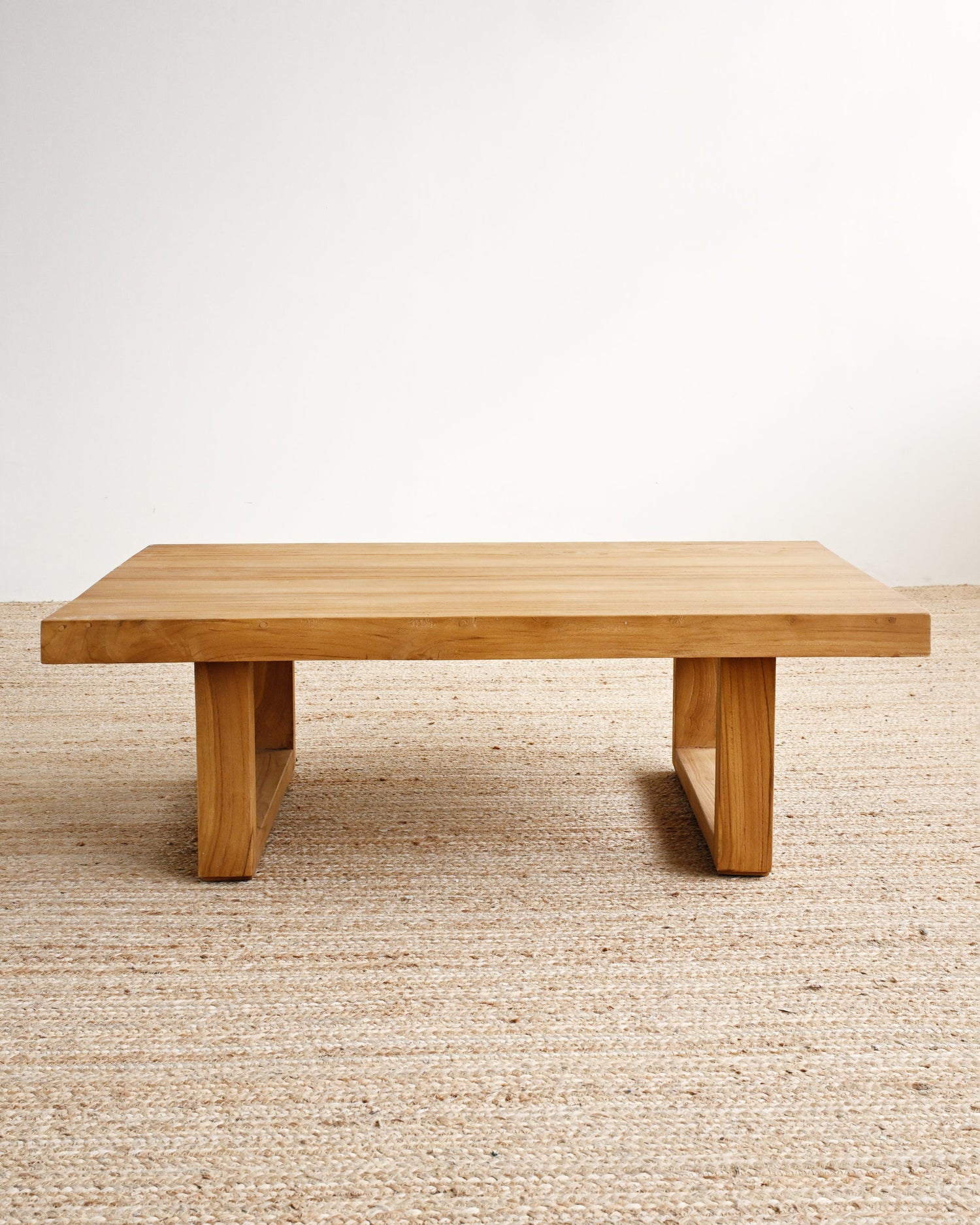 Wooden table on a beige carpet with a white wall background