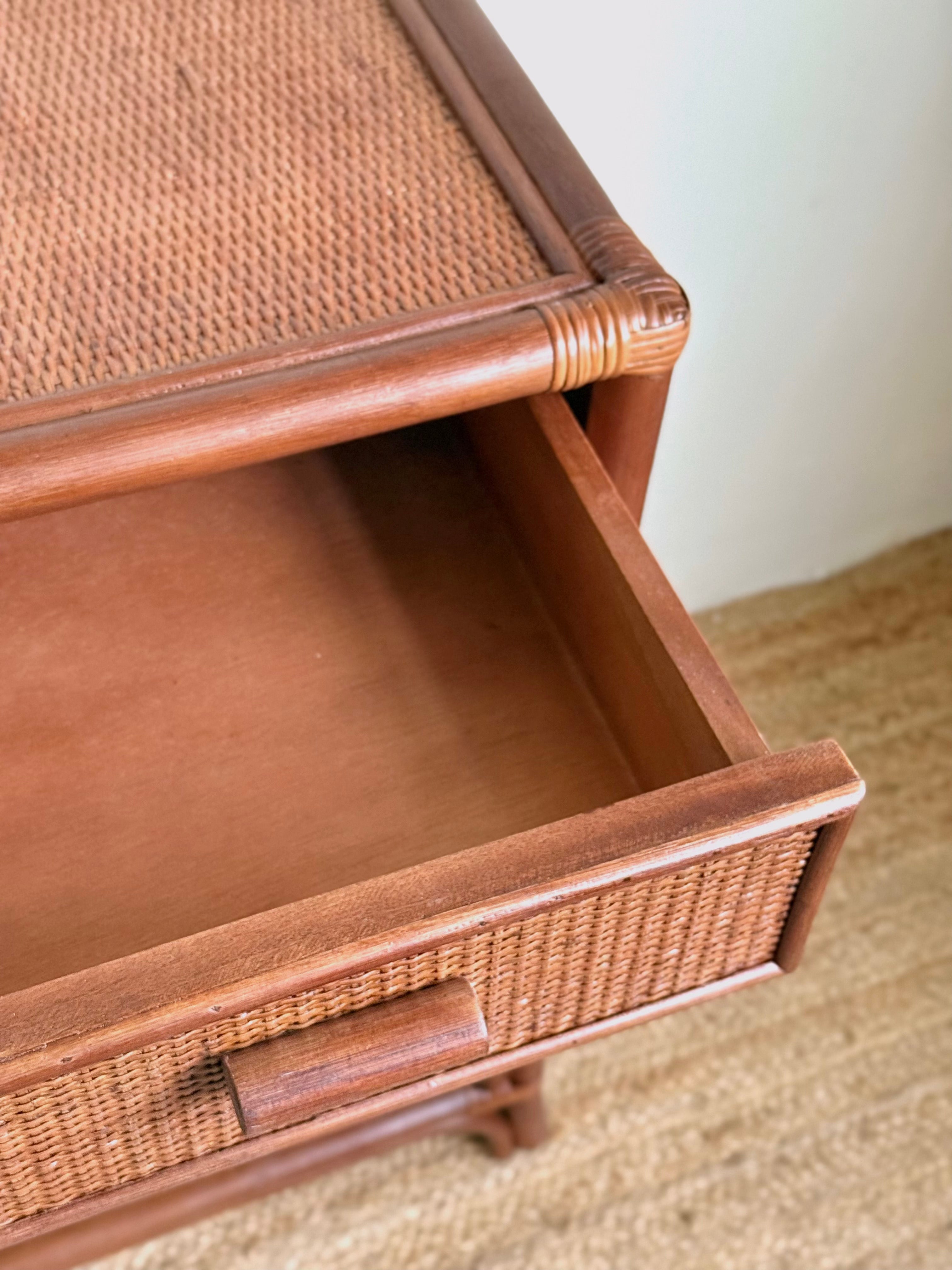 Close-up of a wooden drawer with a woven rattan or cane front panel, shown partially open against a neutral indoor background.