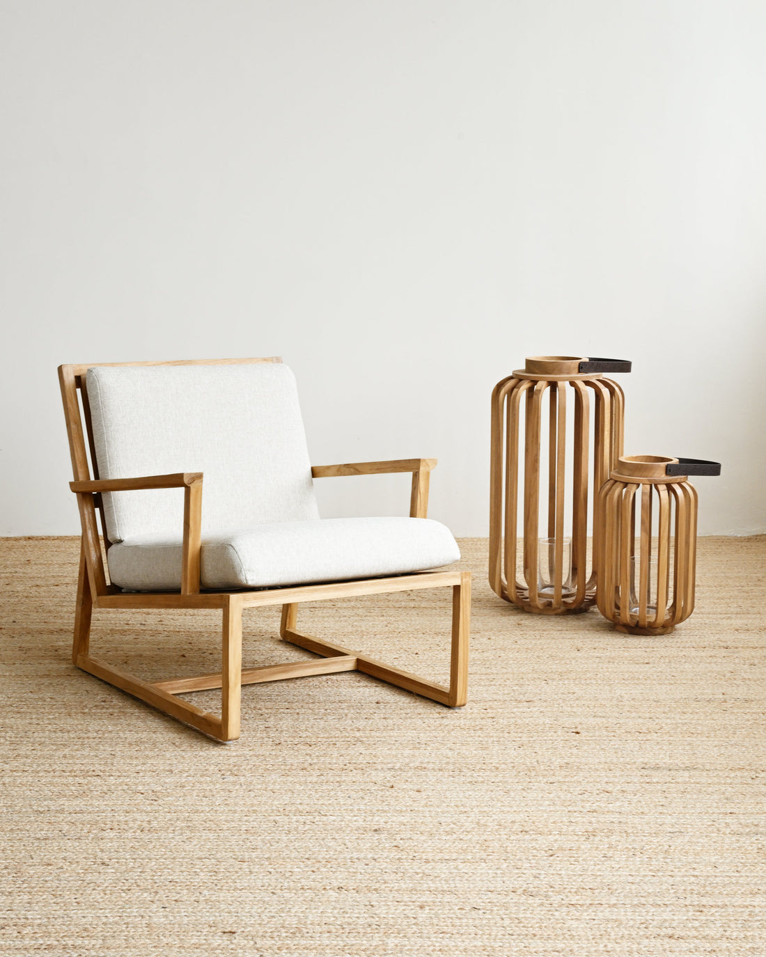 Wooden armchair with white cushion on a light wooden floor, accompanied by two decorative vases.