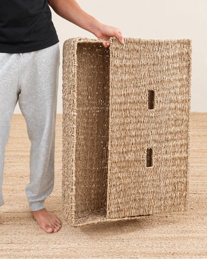 Person holding a woven seagrass box on a beige background