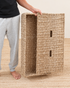 Person holding a woven seagrass box on a beige background