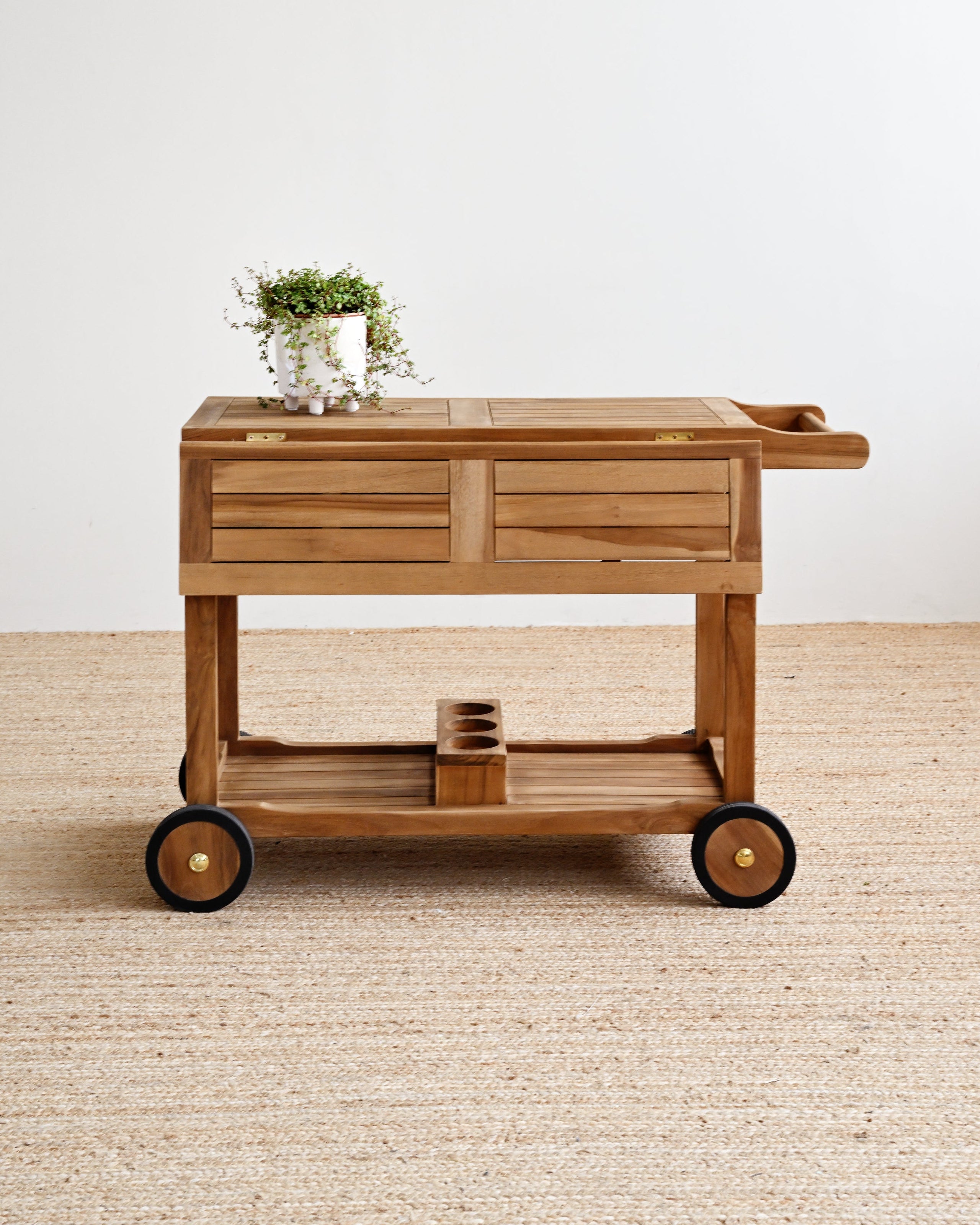 Teak serving cart with wheels on a beige carpet