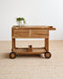 Teak serving cart with wheels on a beige carpet