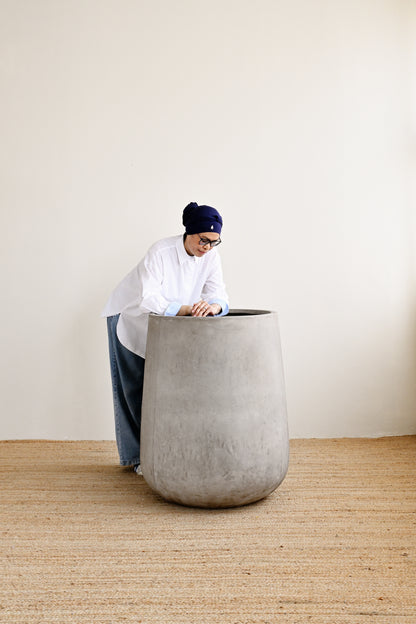 Person interacting with a large concrete planter in a minimalistic setting
