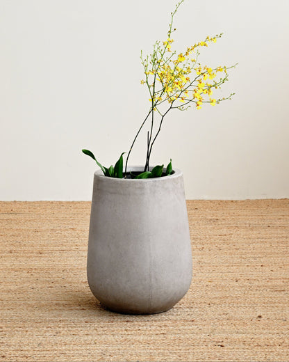 Gray ceramic planter with yellow flowers on a wooden surface