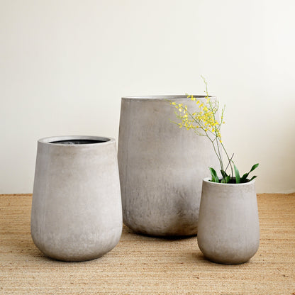 Three concrete planters of different sizes on a wooden surface with a plain background