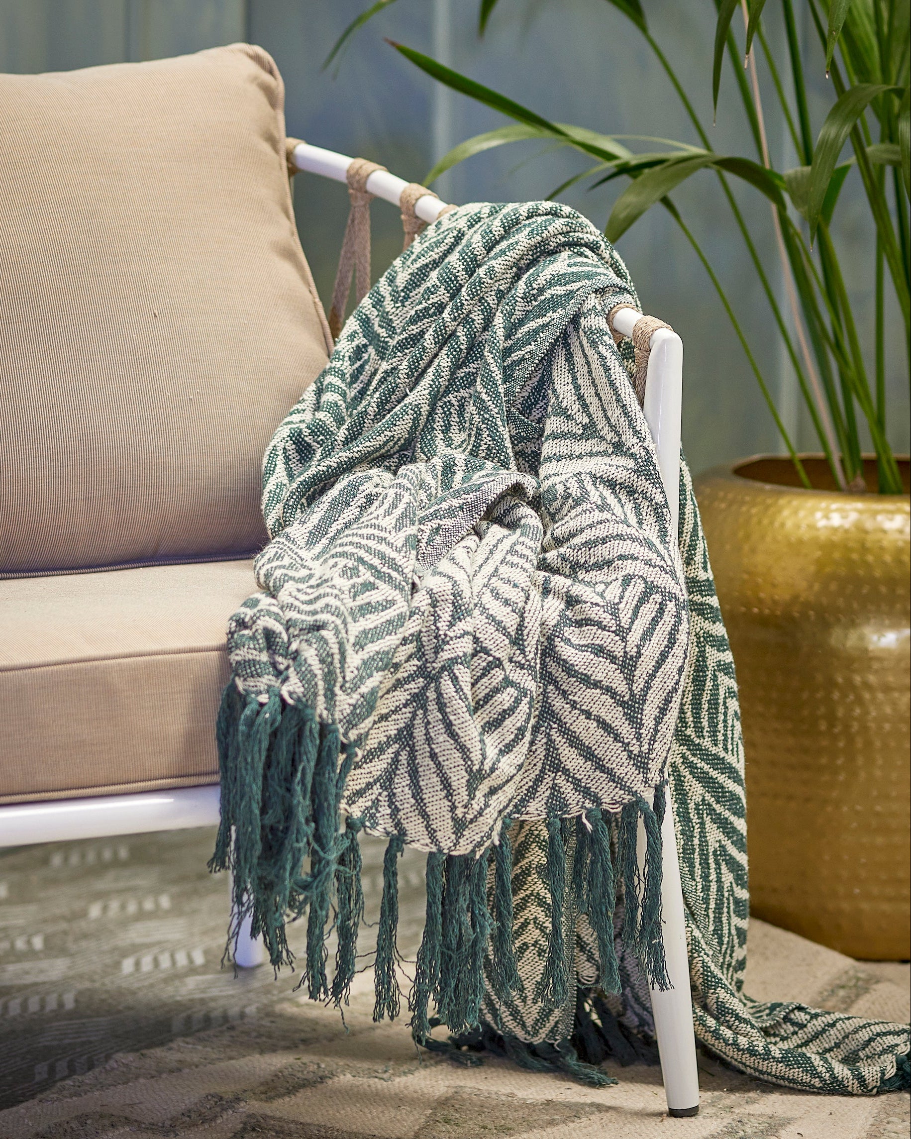 Green patterned throw blanket draped over a chair in a living room setting.