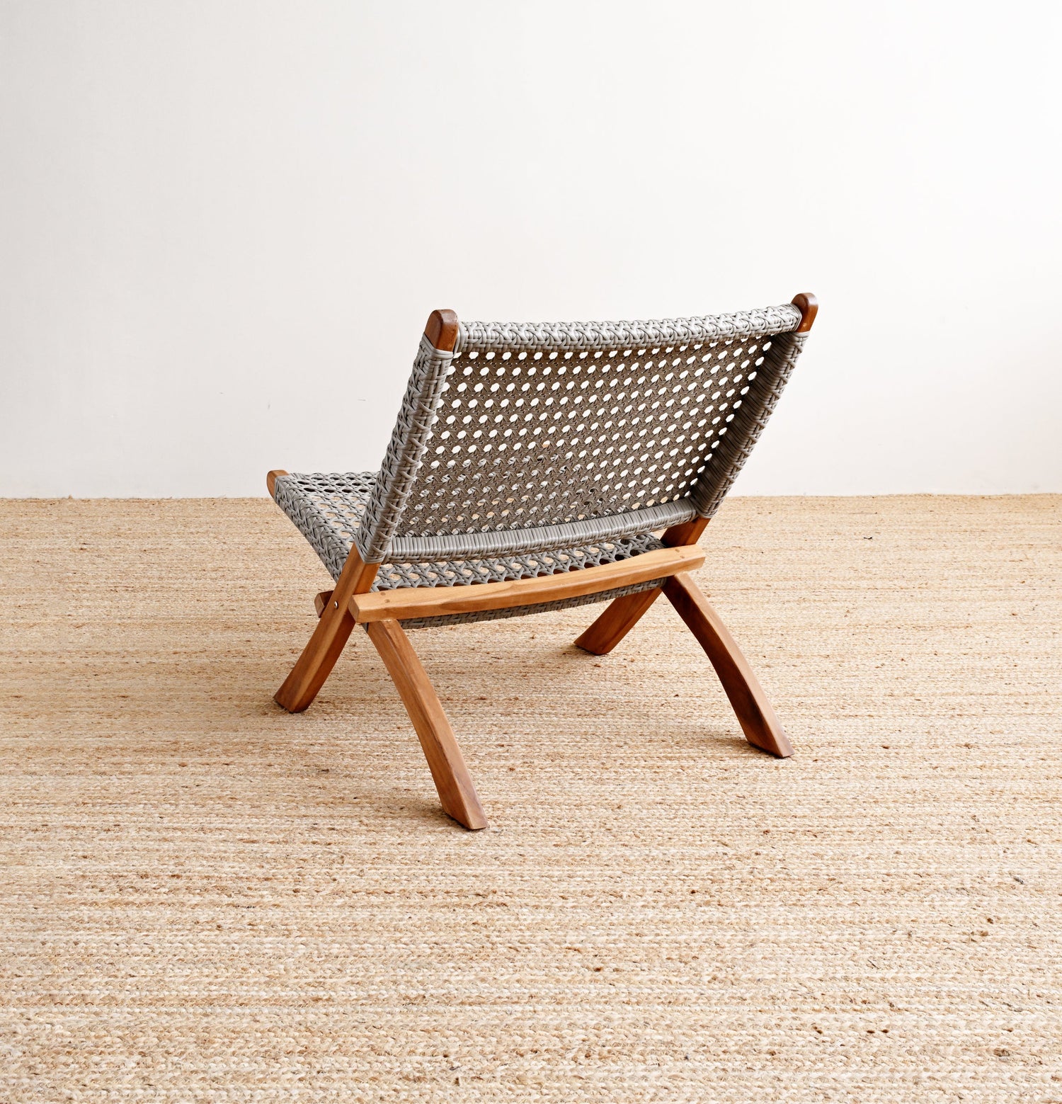 Woven chair on a wooden floor with a white wall background