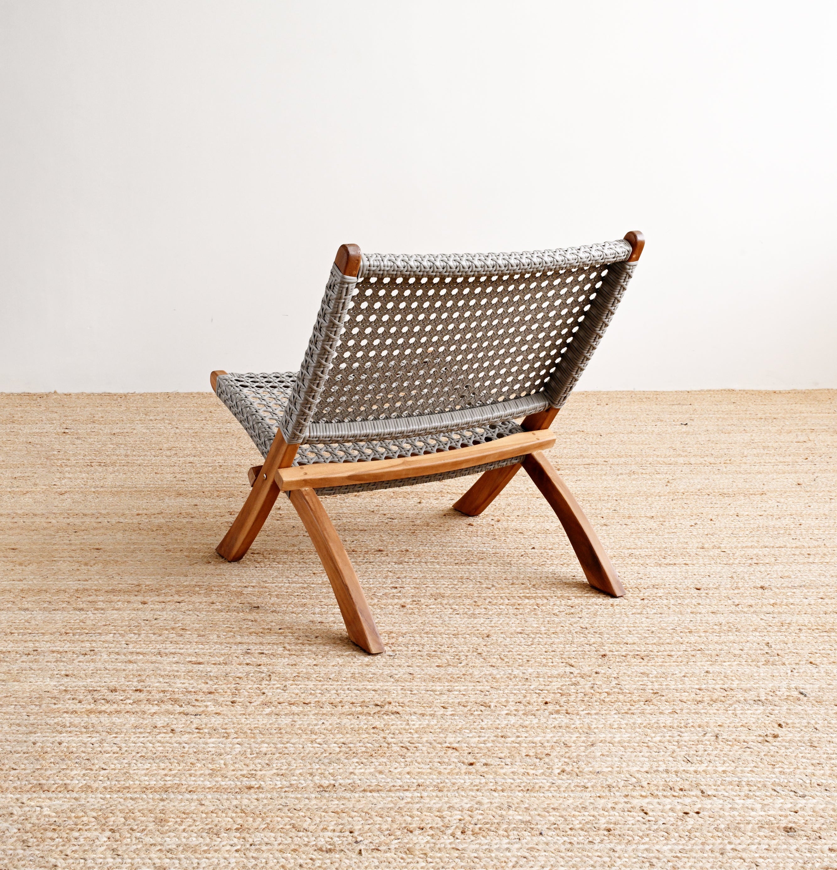 Woven chair on a wooden floor with a white wall background