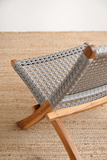 Close-up of a woven chair with wooden frame on a textured surface