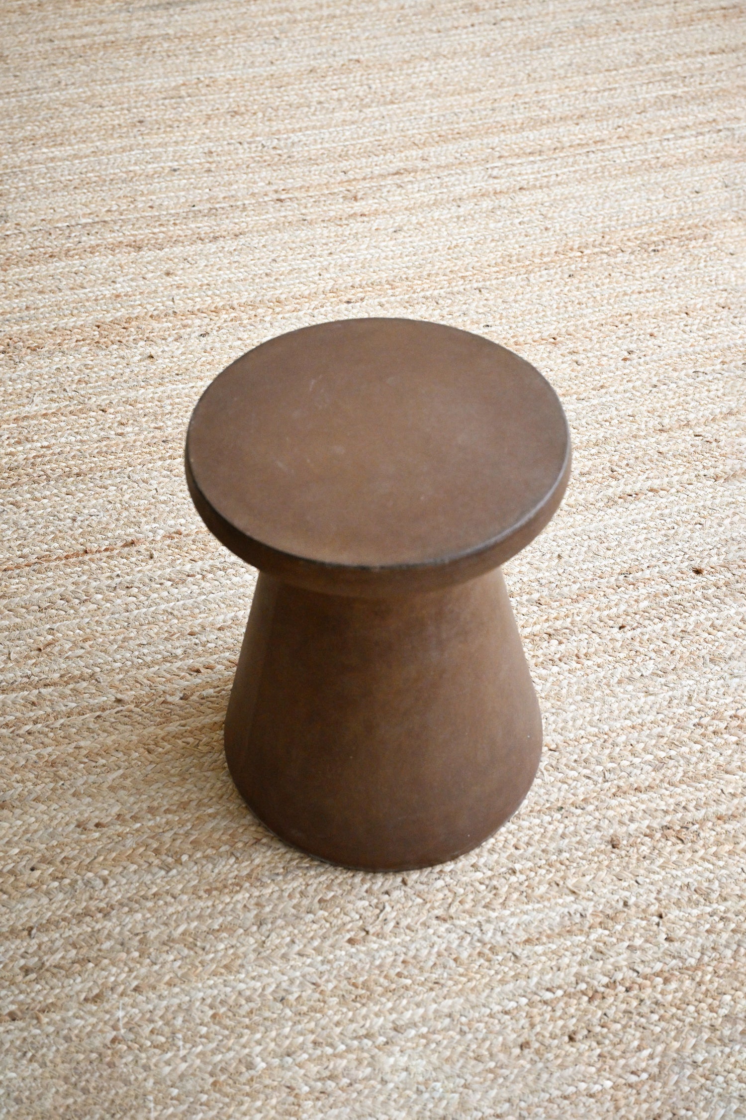Brown cylindrical stool on a textured beige carpet