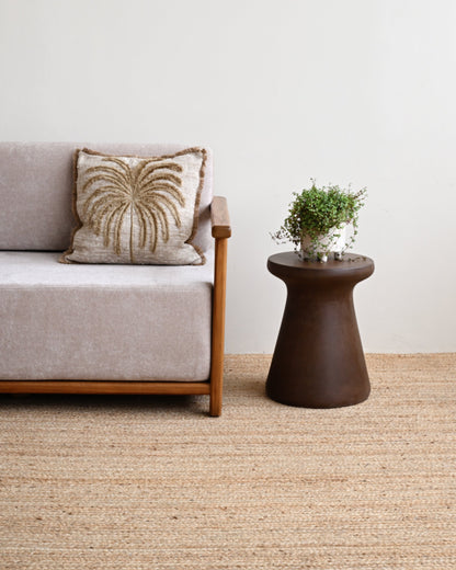 Sofa with decorative pillow and small table with plant on a beige carpet