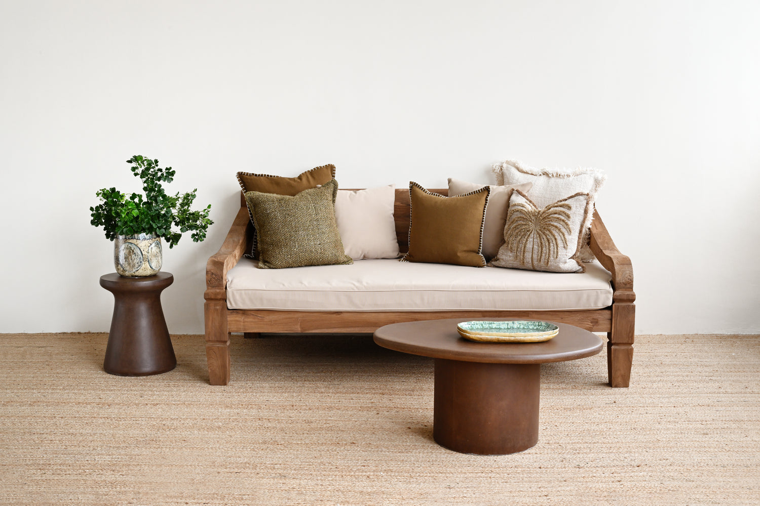 Wooden sofa with cushions in a room with a plant and coffee table.