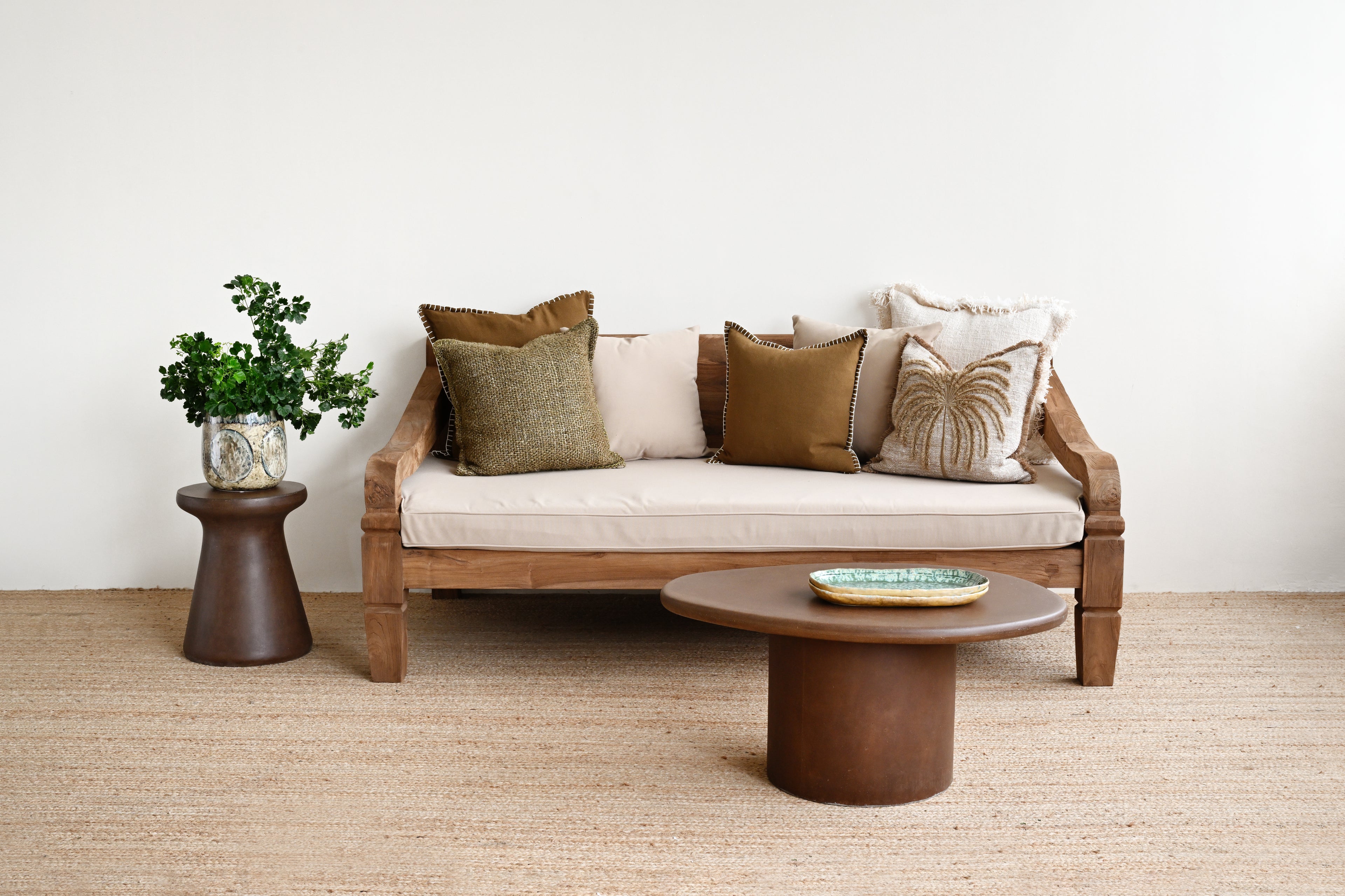 Wooden sofa with cushions in a room with a plant and coffee table.