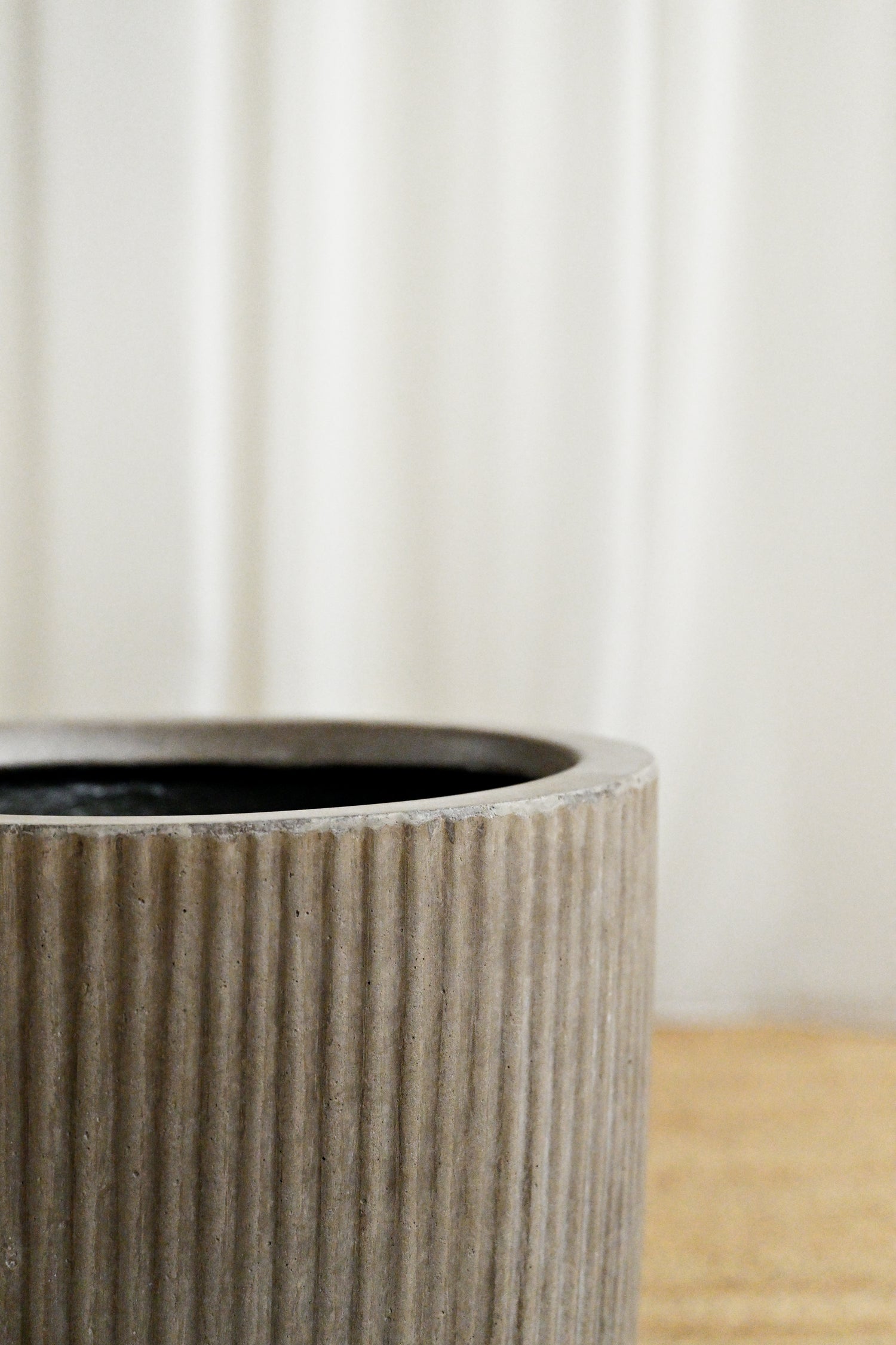Textured ceramic pot on a wooden surface with a neutral background