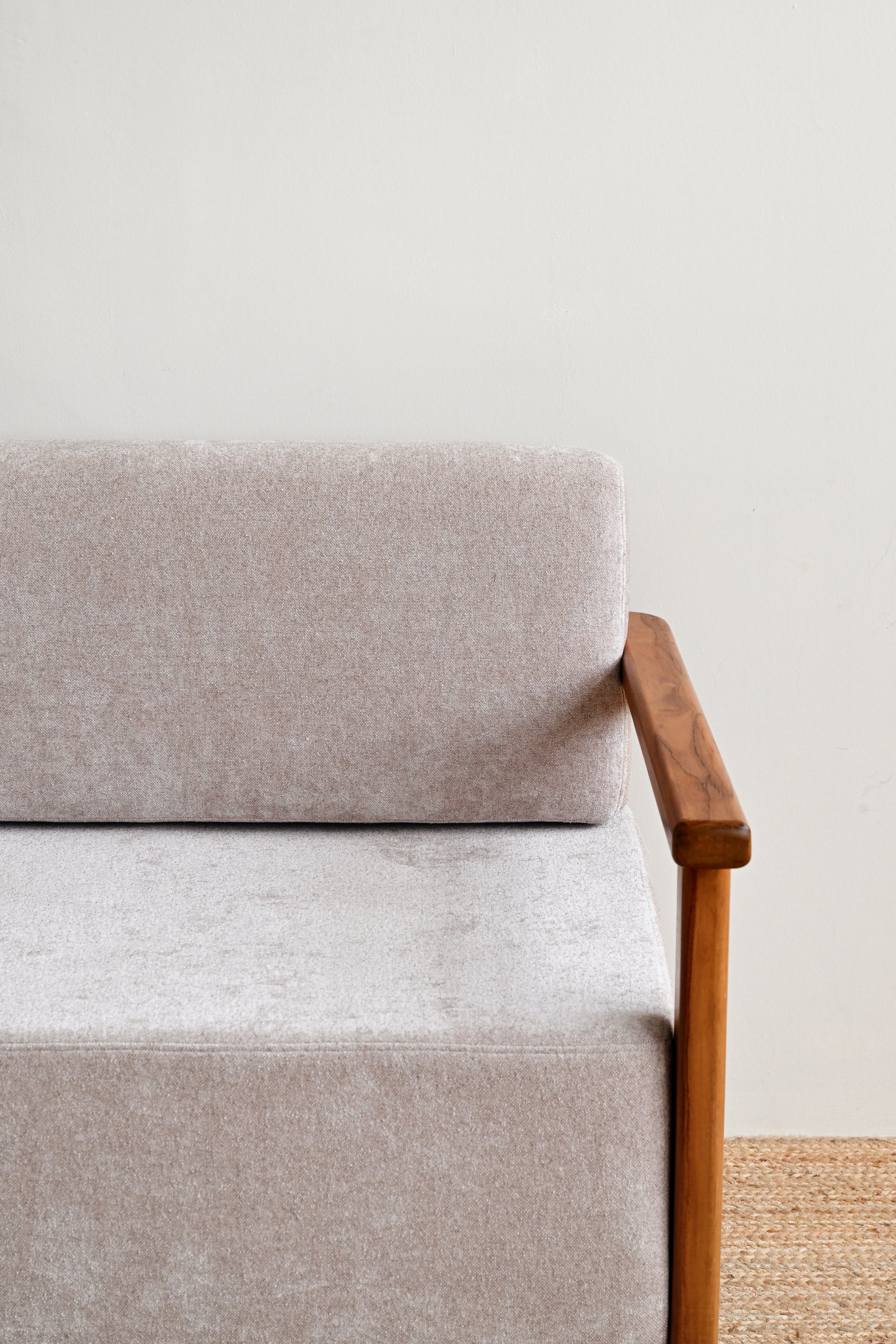 Gray upholstered chair with wooden armrest on a neutral background