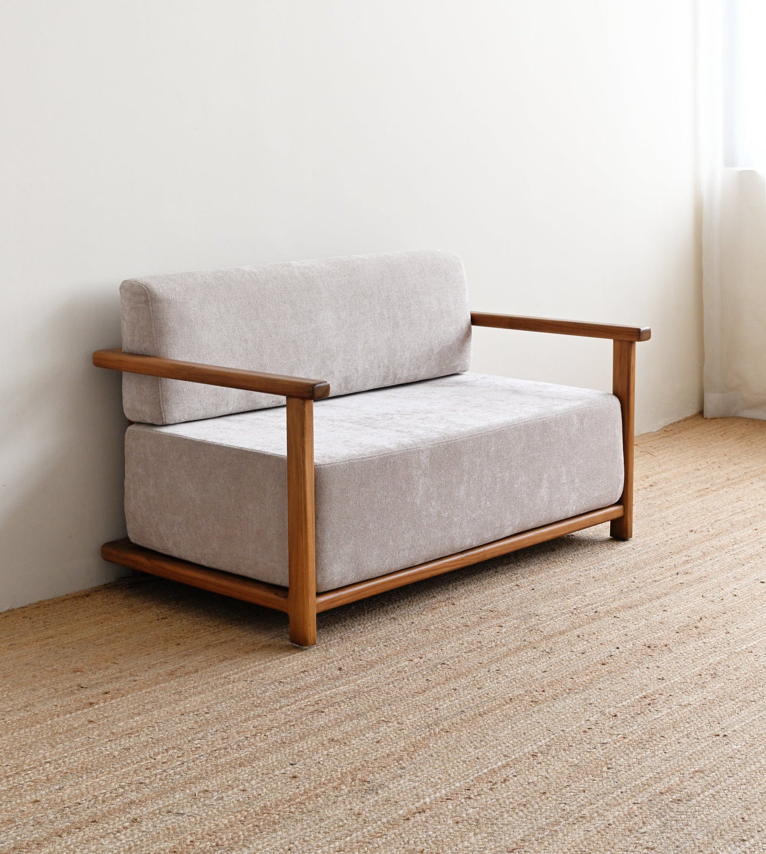 Small sofa with wooden frame and light gray cushions on a beige carpet.