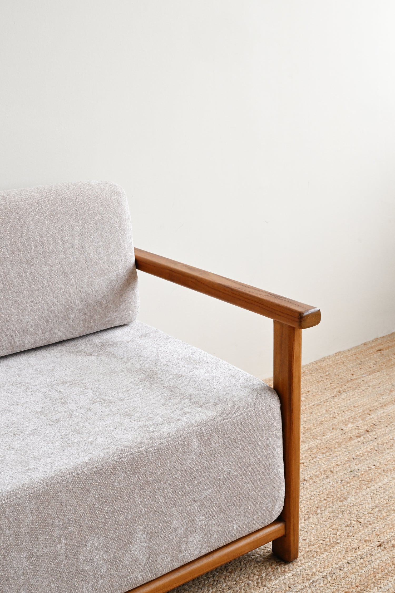 Gray sofa with wooden armrests against a white wall
