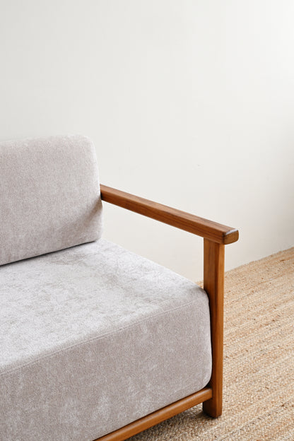 Gray sofa with wooden armrests against a white wall