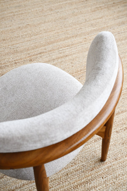 Curved chair with wooden frame and gray cushion on a beige carpet