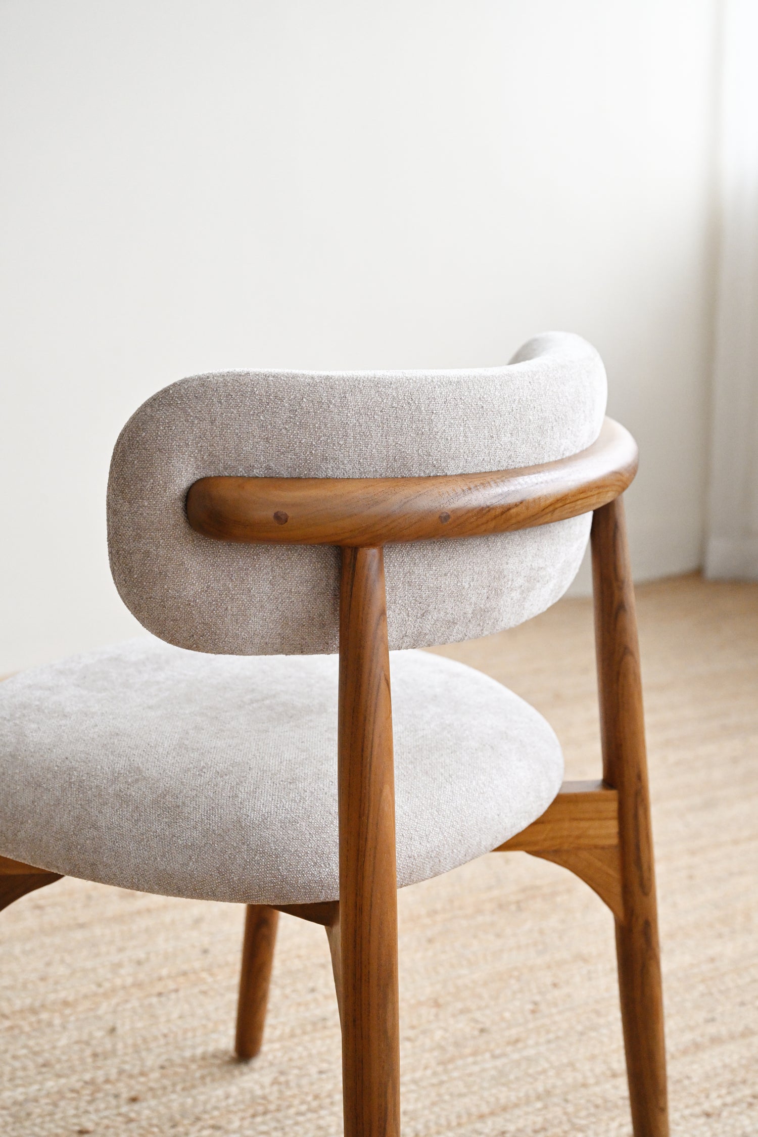 Chair with wooden frame and beige cushion on a light background