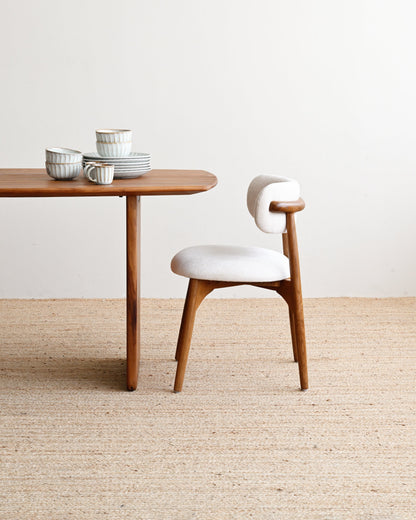 Wooden table with ceramic items and a white chair on a beige carpet.