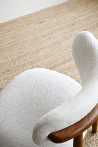 White chair with wooden legs on a textured beige carpet